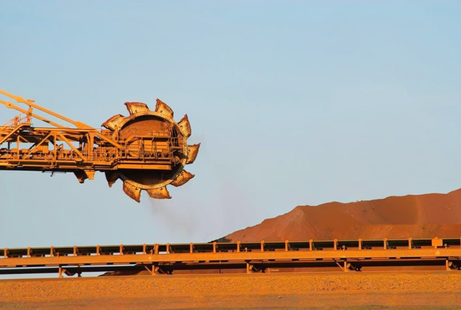 Bucket-wheel reclaimer working an iron ore stockyard at golden hour